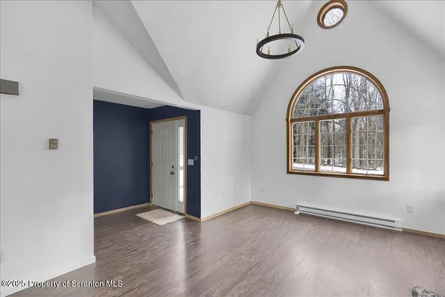 a view of an empty room with a window and wooden floor