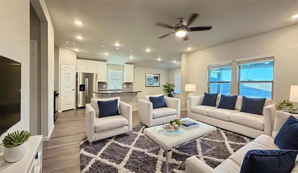 a living room with furniture kitchen view and a large window