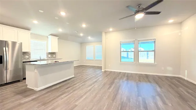 a large kitchen with a center island wooden floor stainless steel appliances and windows