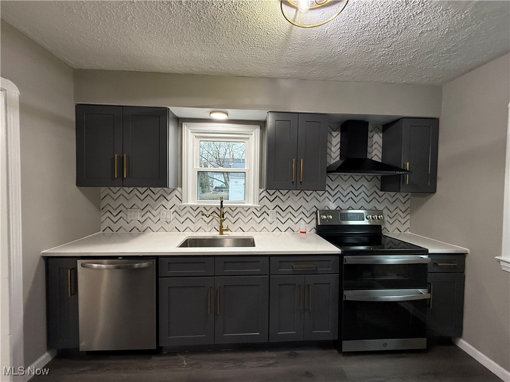 6807 Gerald Avenue Parma, OH 44129 - Photo 5 of 25 Kitchen featuring a sink, light countertops, appliances with stainless steel finishes, wall chimney range hood, and backsplash