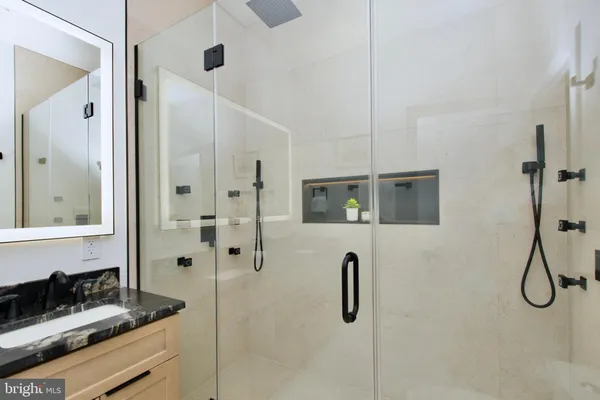 a bathroom with a granite countertop shower sink and mirror