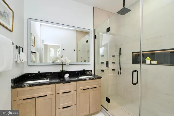 a bathroom with a granite countertop sink a mirror a vanity and a shower