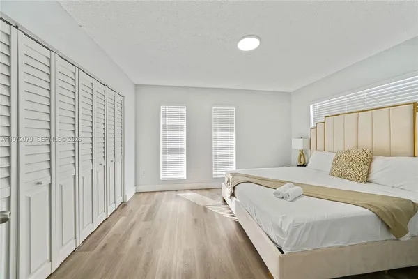 a bedroom with a bed and a large window with wooden floor