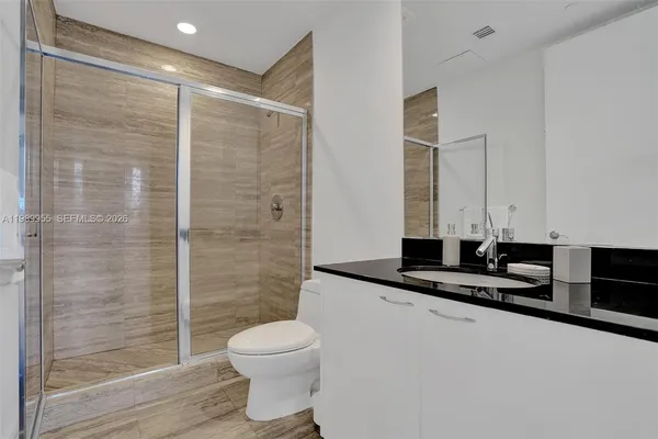 a bathroom with a granite countertop sink a toilet a mirror and shower