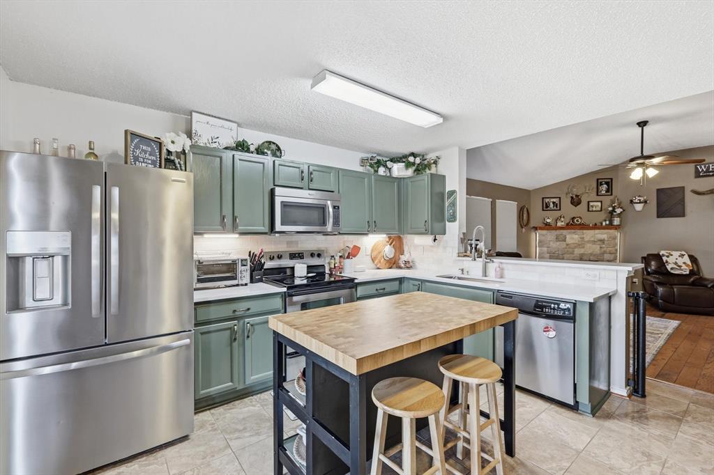 205 Comanche Trail Krum, TX 76249 - Photo 9 of 24 a kitchen with granite countertop a center island and stainless steel appliances