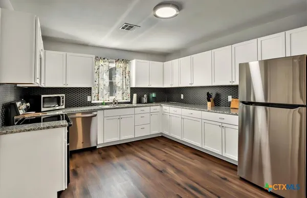 a kitchen with granite countertop white cabinets and white appliances
