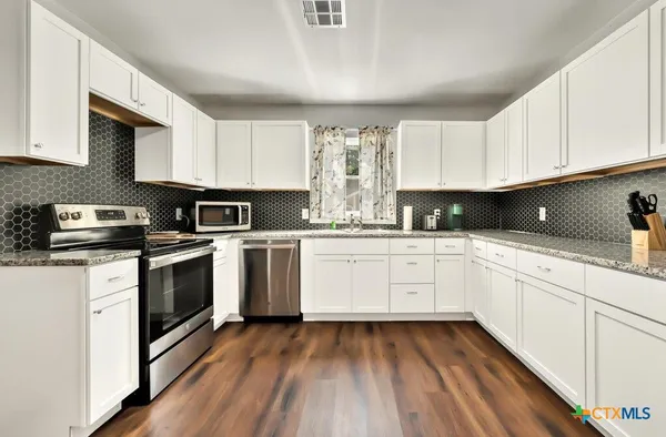 a kitchen with granite countertop white cabinets and white appliances