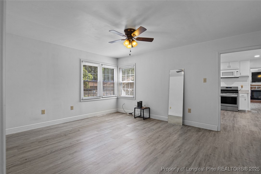 613 East 3rd Avenue Red Springs, NC 28377 - Photo 17 of 37 an empty room with wooden floor a chandelier fan and windows