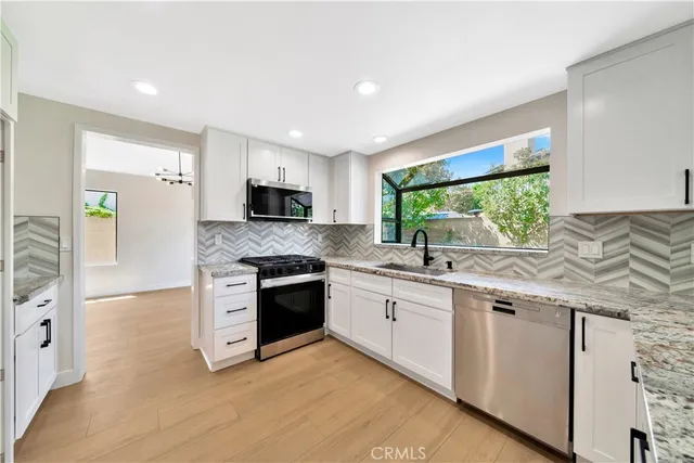 a large kitchen with stainless steel appliances granite countertop a stove a sink and a microwave