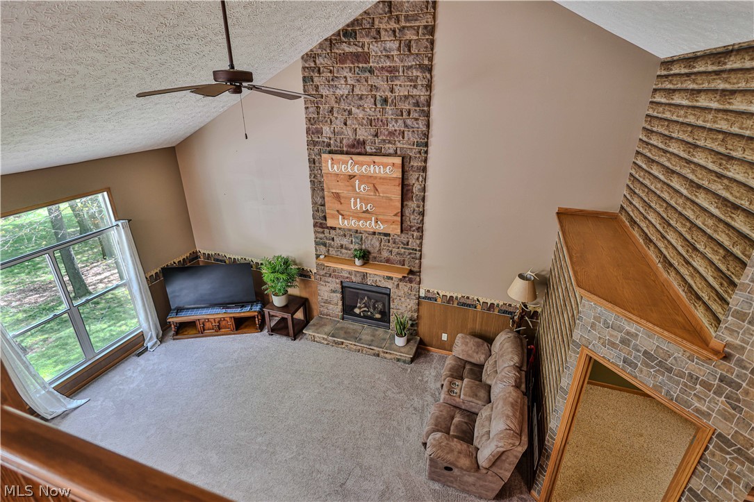 11154 Johnsford Road Southwest Beach City, OH 44608 - Photo 42 of 50 Vaulted living space featuring a stone-clad fireplace with wood mantel, large window, and ceiling fan