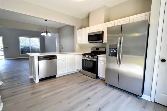 a kitchen with stainless steel appliances wooden floor and a refrigerator