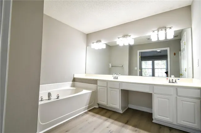 a bathroom with a bathtub a double vanity sink and mirror