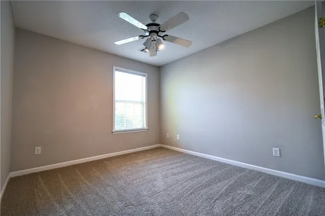 an empty room with a chandelier fan and windows