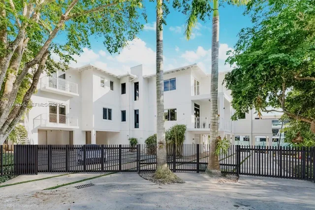 a view of a white building among the street with palm trees
