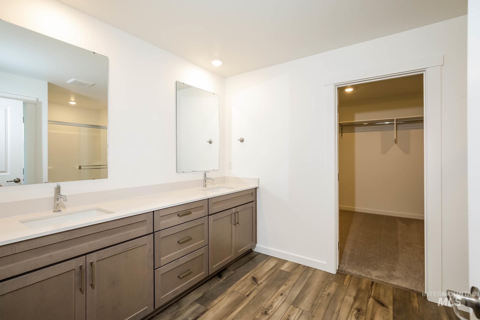 1918 East Springloyd Street Meridian, ID 83642 - Photo 14 of 20 Dual vanities with white countertops, wood-finish flooring, recessed lighting, and an adjacent walk-in closet with built-in shelving