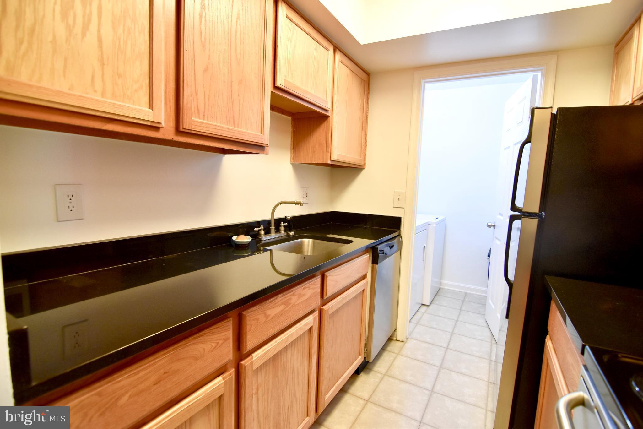 14903 Rydell Road, Unit 204 Centreville, VA 20121 - Photo 4 of 16 a kitchen with granite countertop cabinets a sink and a refrigerator