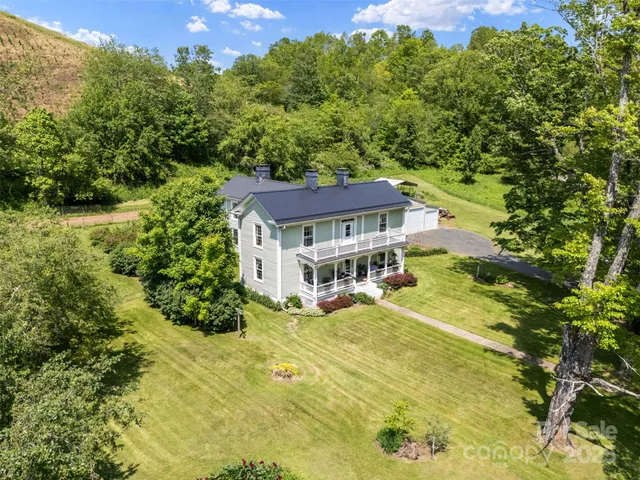 a view of a house with a big yard and large trees