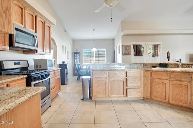 a large kitchen with granite countertop a stove top oven a sink a counter space and cabinets
