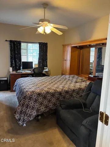 a bedroom with a bed couch chandelier windows and chair