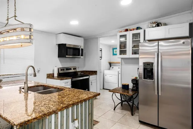 a kitchen with stainless steel appliances granite countertop a sink a stove and a refrigerator