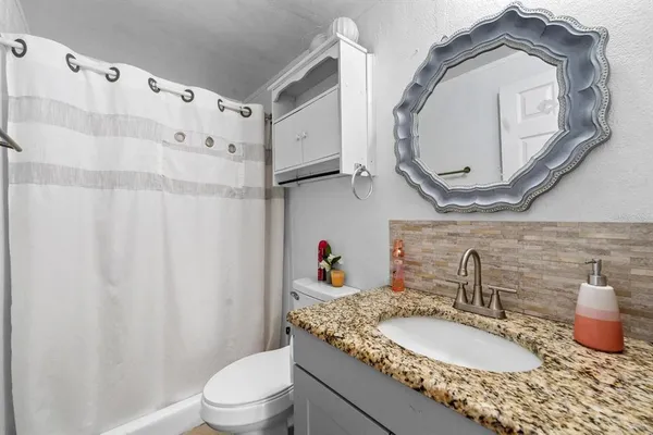 a bathroom with a granite countertop sink a toilet and a mirror