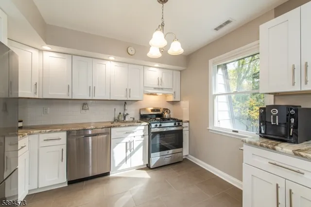 a kitchen with granite countertop a stove and white cabinets