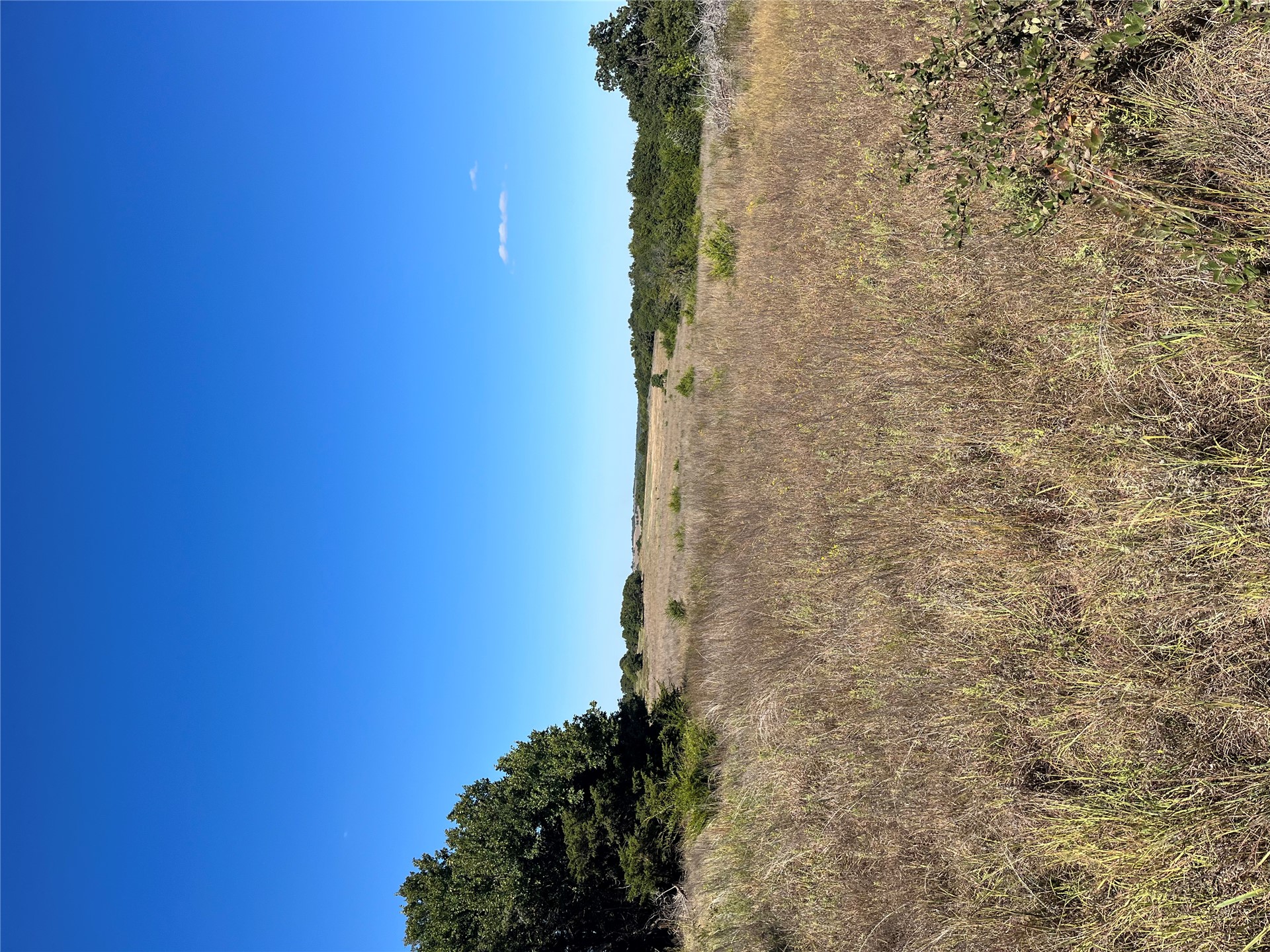 0 Range Road Perry, OK 73077 - Photo 20 of 32 Expansive open land featuring diverse vegetation and distant tree lines under a clear sky
