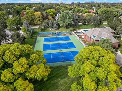 an aerial view of a residential houses with outdoor space and trees