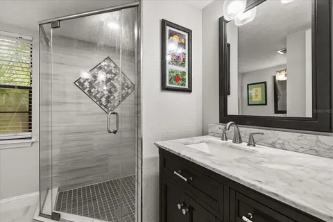 a bathroom with a granite countertop sink a mirror and shower