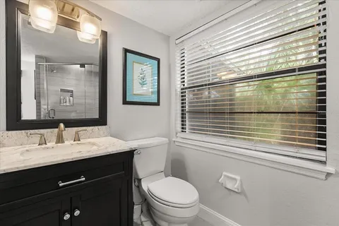 a bathroom with a sink a toilet a mirror and a window