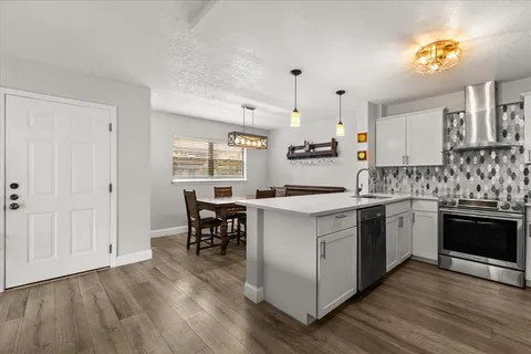 a kitchen with stainless steel appliances granite countertop a stove a sink dishwasher and a refrigerator with wooden floor