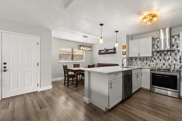 a kitchen with stainless steel appliances granite countertop a stove a sink dishwasher and a refrigerator with wooden floor