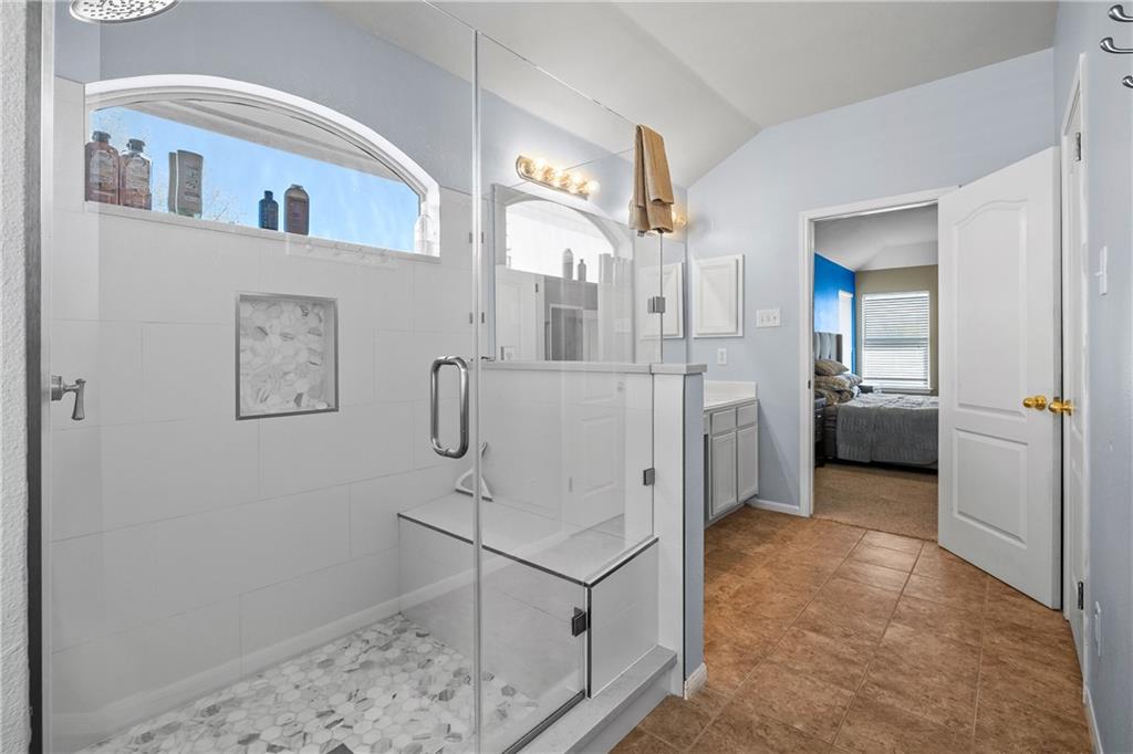 3508 Bratton Ridge Crossing Austin, TX 78728 - Photo 11 of 18 A well-appointed primary bathroom showcases a glass-enclosed shower with a built-in bench and an arched window.