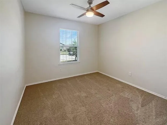 an empty room with a window and a fan