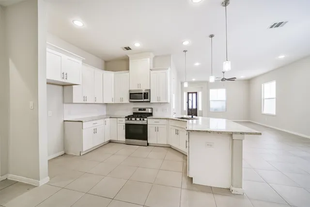 a kitchen with kitchen island granite countertop a stove sink and cabinets