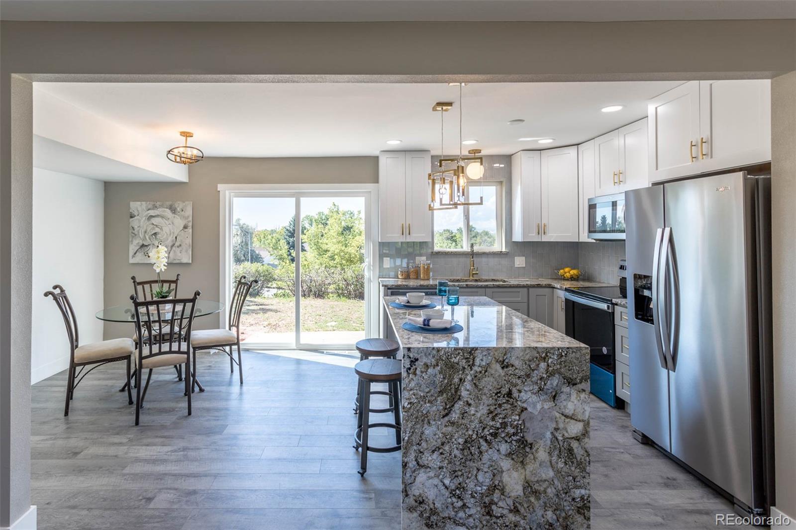 4465 South Eagle Circle Aurora, CO 80015 - Photo 9 of 26 a kitchen with granite countertop a refrigerator a stove a dining table and chairs with wooden floor