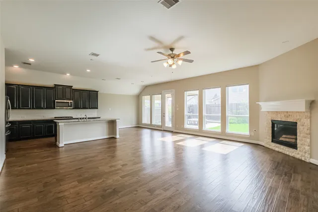 a view of an empty room with a kitchen and a fireplace