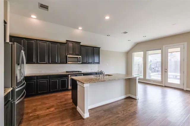 a kitchen with stainless steel appliances granite countertop a stove refrigerator sink and cabinets