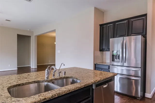 a kitchen with stainless steel appliances granite countertop a refrigerator a sink and a stove