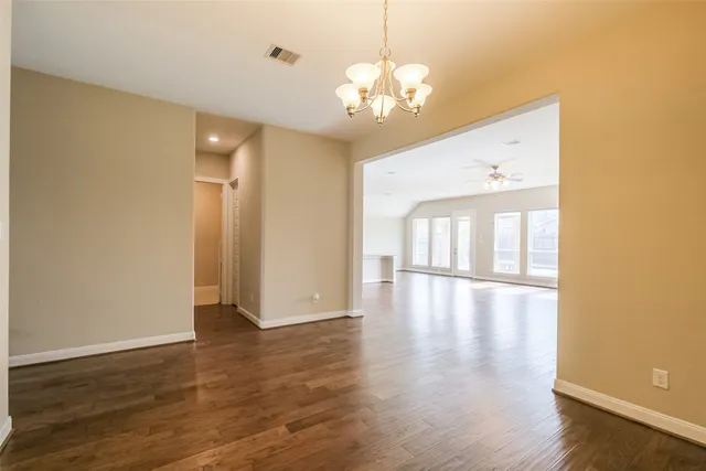 a view of an empty room with window and wooden floor
