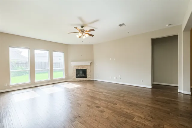 a view of an empty room with a window and wooden floor