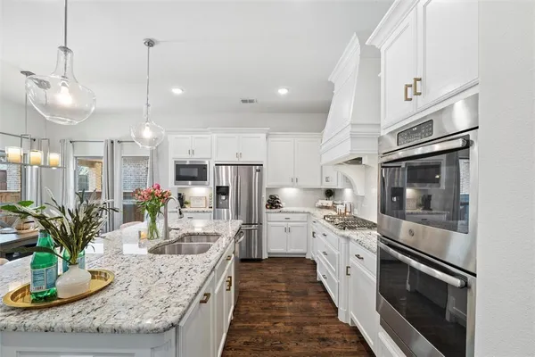 a kitchen with stainless steel appliances granite countertop a sink a stove and a wooden floors
