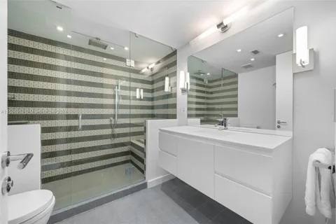 a bathroom with a sink a toilet a mirror and shower