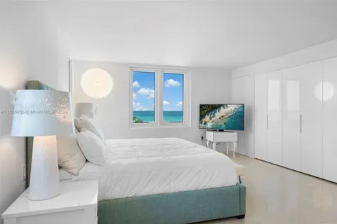 a bedroom with a bed and a flat tv screen on dresser