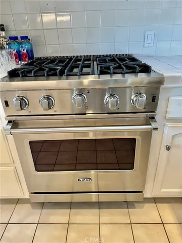 a kitchen with stainless steel appliances granite countertop a coffee maker a sink and white cabinets