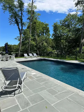 a view of a swimming pool with a table and chairs under an umbrella