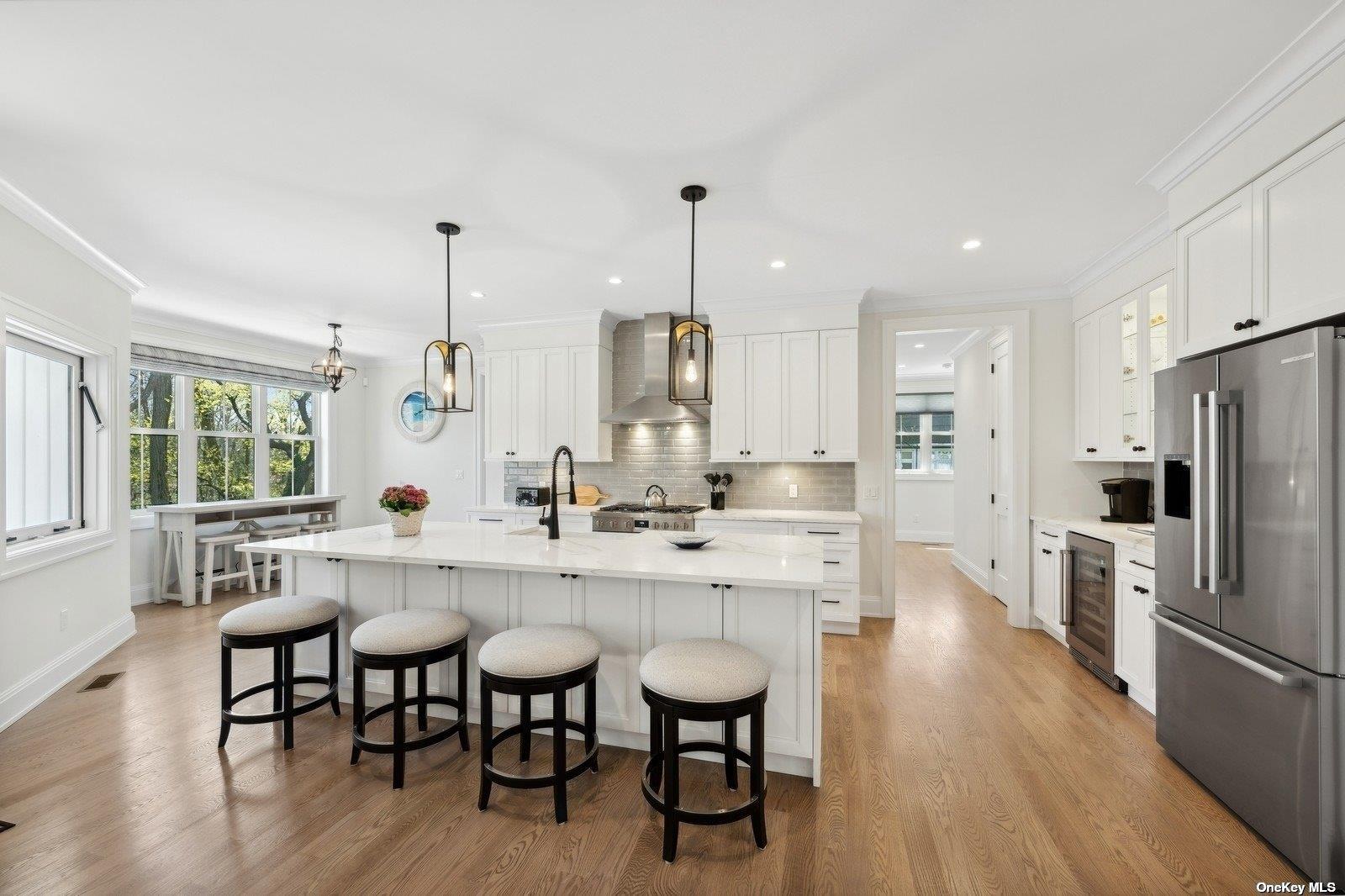 910 Glenn Road Southold, NY 11971 - Photo 8 of 33 a kitchen with stainless steel appliances a dining table chairs a sink and dishwasher a refrigerator with wooden floor