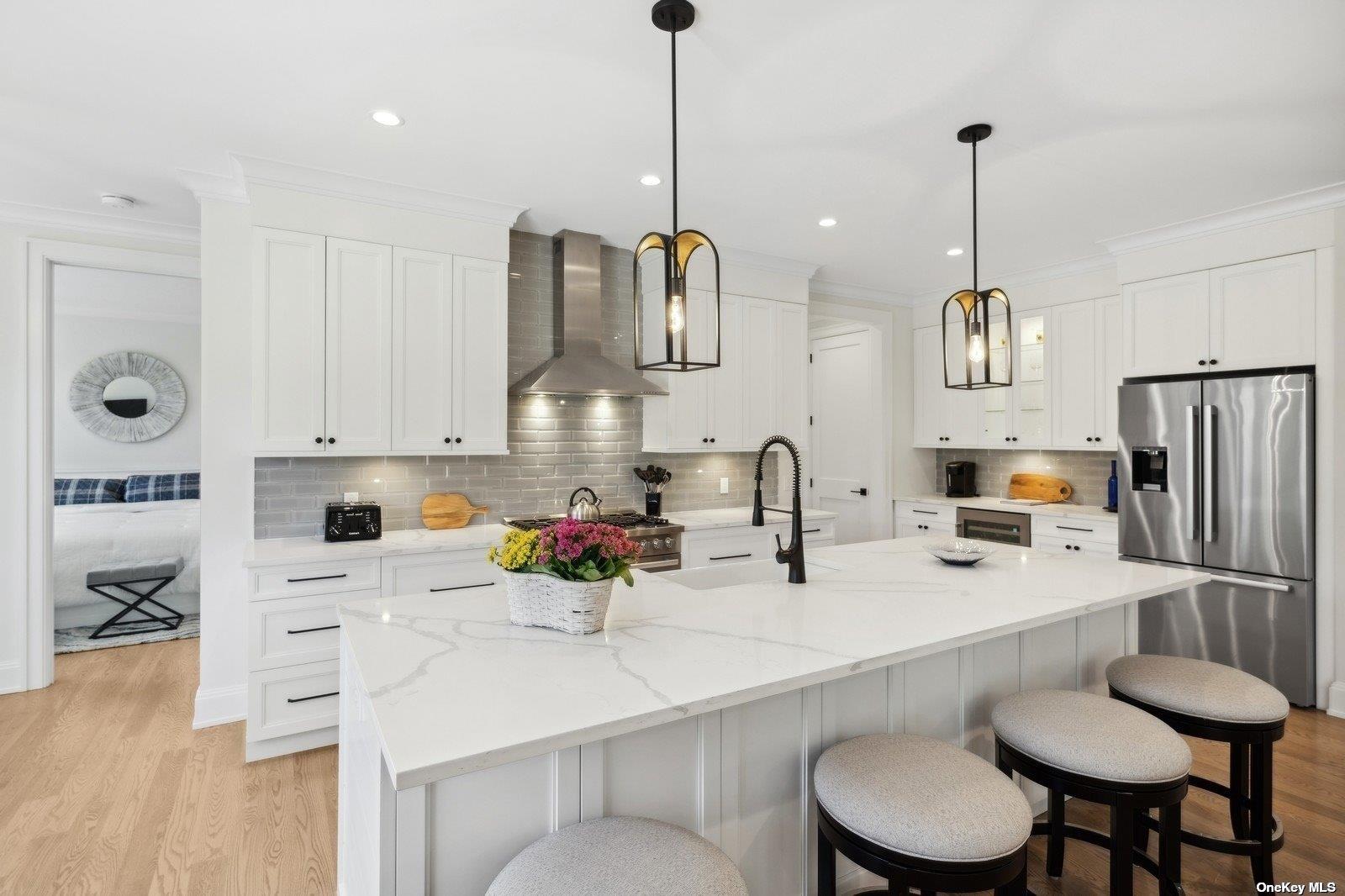910 Glenn Road Southold, NY 11971 - Photo 10 of 33 a kitchen with a sink a stove a refrigerator and white cabinets with wooden floor