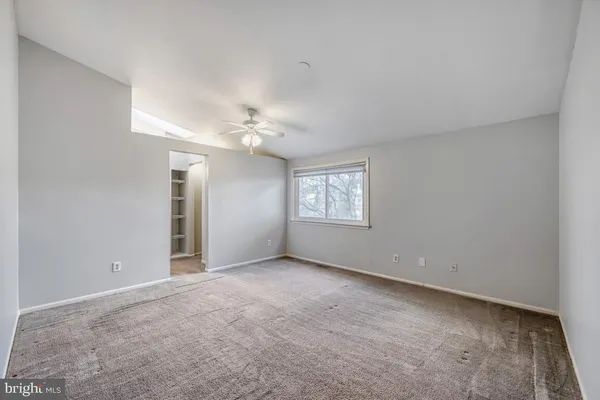 an empty room with windows and chandelier fan