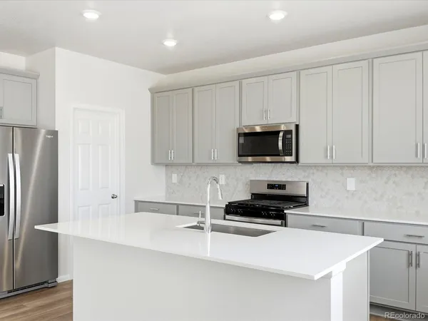 a kitchen with granite countertop a refrigerator sink and white cabinets